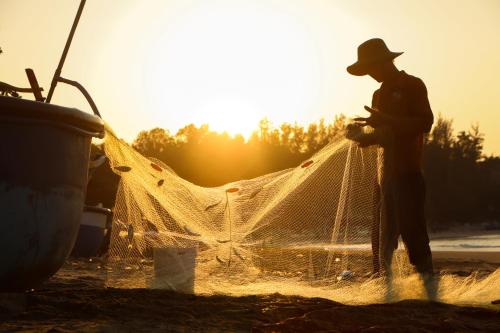a man standing next to a net on the beach at Stop And Go Lang Chai Boutique Resort in Phan Thiet