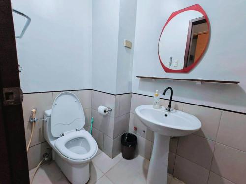 een badkamer met een toilet, een wastafel en een spiegel bij Baguio Condotel - City Center in Baguio