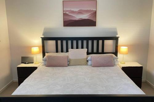 a bedroom with a large white bed with two lamps at Large and stylish Townhouse in chic area in Brisbane