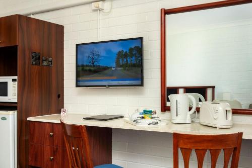 a kitchen with a counter with a tv on a wall at Pigeon House Motor Inn in Ulladulla