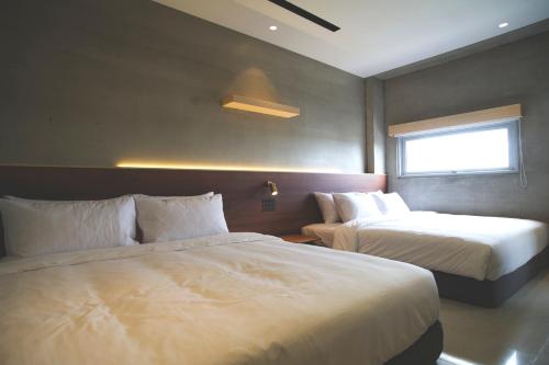 a hotel room with two beds and a window at FFF Hotel in Hengchun