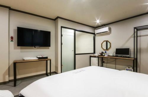 a bedroom with a large bed and a flat screen tv at The Sharp Hotel in Changwon