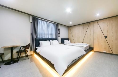 a bedroom with a large white bed and a desk at The Sharp Hotel in Changwon