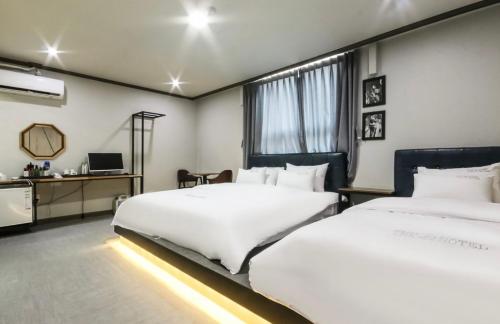 a hotel room with two beds and a desk at The Sharp Hotel in Changwon