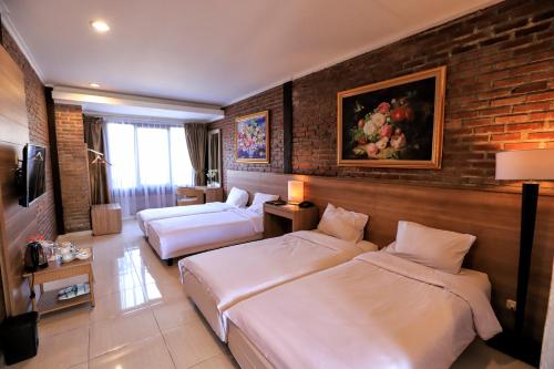 a hotel room with two beds and a brick wall at Ciwidey Valley Resort Hot Spring Waterpark in Bandung