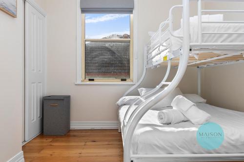 a white bunk bed in a room with a window at Charming Merewether Cottage in Merewether