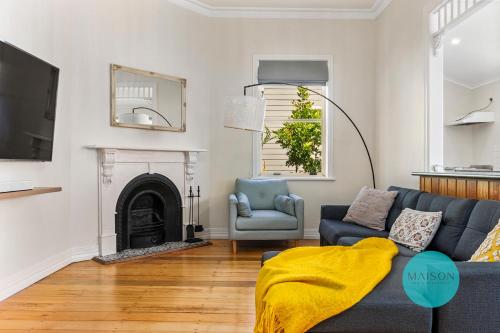 a living room with a blue couch and a fireplace at Charming Merewether Cottage in Merewether