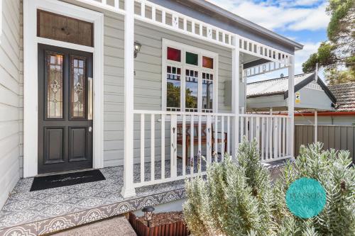 a house with a front porch with a black door at Charming Merewether Cottage in Merewether