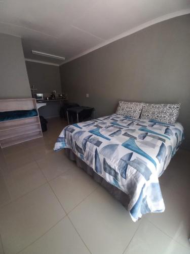 a bedroom with a bed with a blue and white comforter at Dafel street Guesthouse in Piet Retief