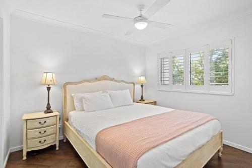 a white bedroom with a bed and two night stands at Coastal 1-Bed Apartment with Pool & Tennis Court in Gold Coast
