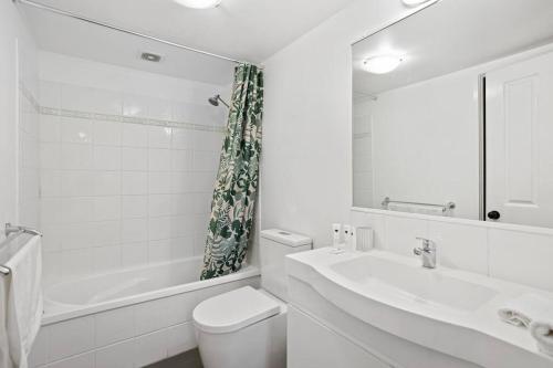 a bathroom with a sink and a toilet and a mirror at Coastal 1-Bed Apartment with Pool & Tennis Court in Gold Coast