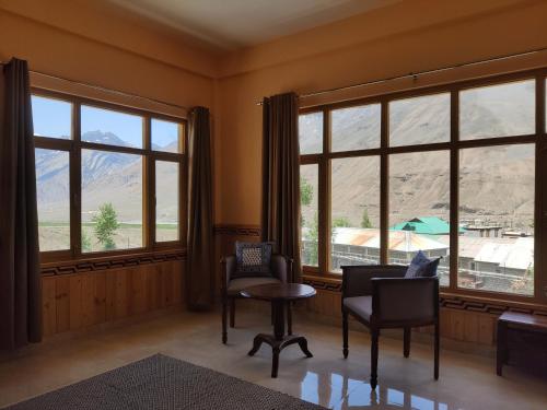 a living room with windows and a table and chairs at Hotel Spiti Heritage in Kaza
