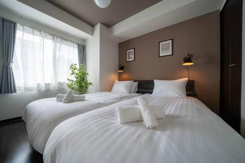 two large white beds in a bedroom with a window at Norwegian Wood in Kita-sanjō