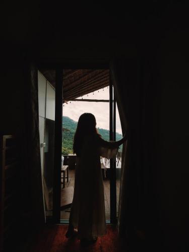 a woman standing in a room looking out a door at U Garden in Ban Huai Khai