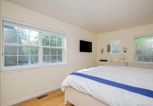 a white bedroom with a large bed and two windows at Villa Baloch- w/ Sparkling heated pool in East Hampton