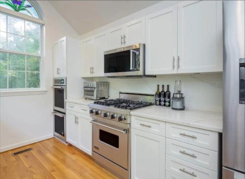 a kitchen with white cabinets and a stove top oven at Villa Baloch- w/ Sparkling heated pool in East Hampton