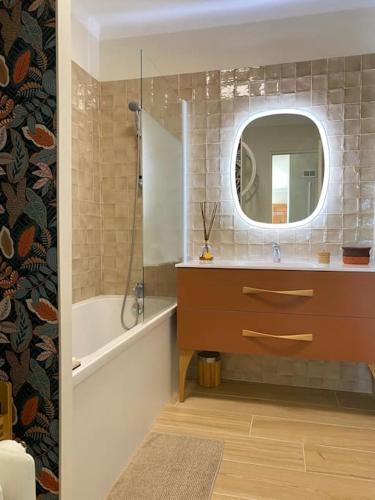 une salle de bain avec un lavabo, un miroir et une baignoire dans l'établissement Maison spacieuse avec piscine pour 4 à 8 personnes, à Saint-Laurent-des-Arbres