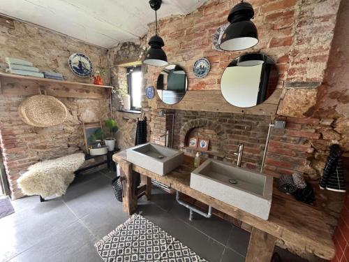 La salle de bains est pourvue d'un lavabo et d'un mur en briques. dans l'établissement Le Brasseur Logements - Tents, à Saint-Caprais