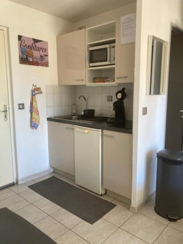 a small kitchen with white cabinets and a microwave at Le Ciel Bleu in La Seyne-sur-Mer