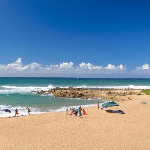 a group of people on a beach near the ocean at Tranquility - Banana Beach Club in Port Shepstone
