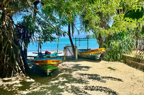 two boats parked on a beach near the water at Namaskara by the Beach - Charming Beachfront Bungalow Retreat in Moraketiara