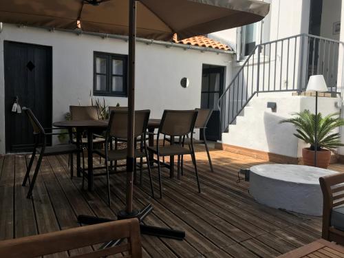 un patio avec une table, des chaises et un parasol dans l'établissement Le 64, à Châtelaillon-Plage