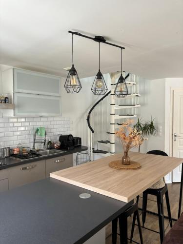 a kitchen with a wooden table and three lights at Appartement duplex cosy Saint Servan centre in Saint Malo
