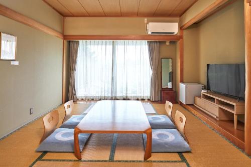 a dining room with a table and a television at IKOI Villa in Karuizawa