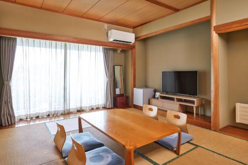 a living room with a wooden table and a television at IKOI Villa in Karuizawa