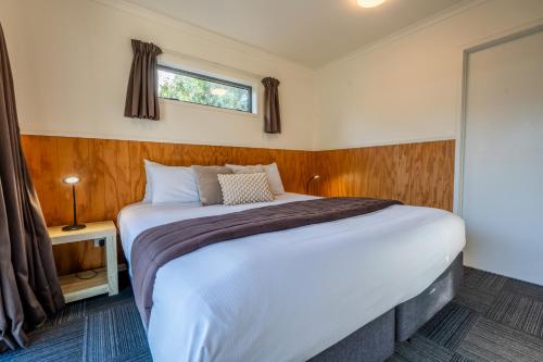 a bedroom with a large bed with a window at Tasman Holiday Parks - Coromandel in Coromandel Town