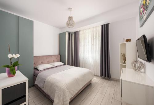 a white bedroom with a bed and a tv at A&A Luxury Apartment in Giroc