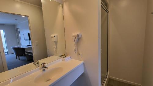 a bathroom with a sink and a mirror and a phone at Manukau Motor Lodge in Auckland