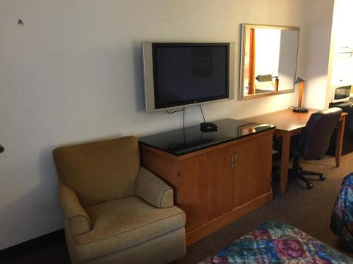 a room with a tv and a chair and a desk at Sunshine Motel in Fife