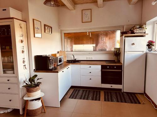 a kitchen with white cabinets and a white refrigerator at Wanderlust Cottage Avrig in Avrig