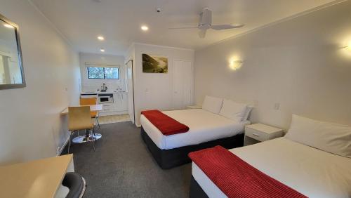 a hotel room with two beds and a desk at Manukau Motor Lodge in Auckland