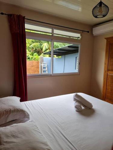a bedroom with a white bed and a window at Maison du bonheur Moorea in Vairoa
