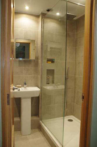 a bathroom with a shower and a sink and a glass shower door at Stylish Garden Apartment, Exmouth - 'Little Monty' in Exmouth