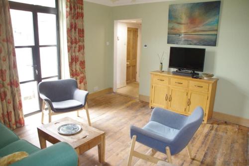 a living room with two chairs and a tv at Stylish Garden Apartment, Exmouth - 'Little Monty' in Exmouth