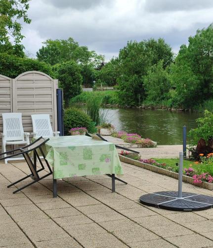 a table and two chairs next to a river at Appartement spacieux à La Taillée avec jardin et vélos in La Taillée