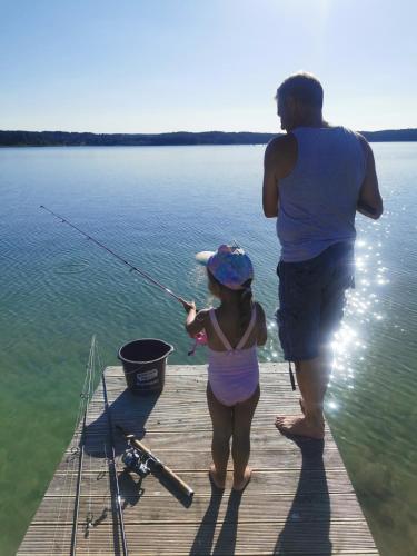 a man and a little girl fishing on a dock at Ośrodek Wypoczynkowy "U Kulasa" in Warchały
