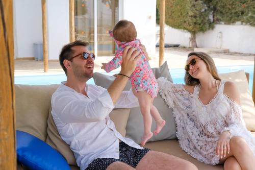 a man and woman sitting on a couch holding a baby at Thalassines Villas in Ayia Napa