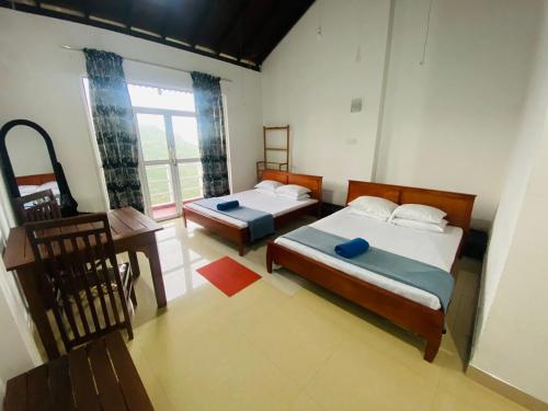 a bedroom with two beds and a desk and a window at Grand Glorious in Haputale