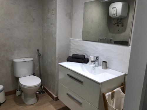 a bathroom with a toilet and a sink and a mirror at Casa BAU in Los Pocillos