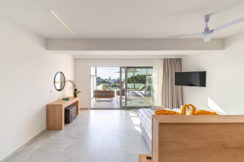 a bedroom with a bed and a tv and a balcony at Thimios Suites Adults Only in Acharavi