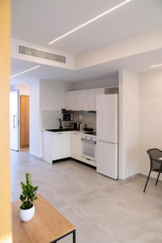an open kitchen with white appliances and a table at Thimios Suites Adults Only in Acharavi