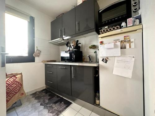 une cuisine avec un réfrigérateur et un micro-ondes dans l'établissement Appartement lumineux avec balcon, à Levallois-Perret