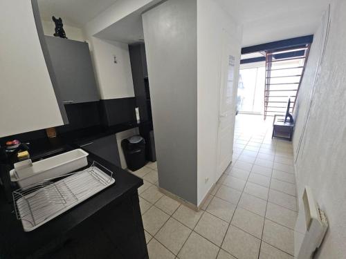 une salle de bain avec un comptoir noir et un sol en carrelage blanc dans l'établissement Appartement sur la plage, à Fos-sur-Mer