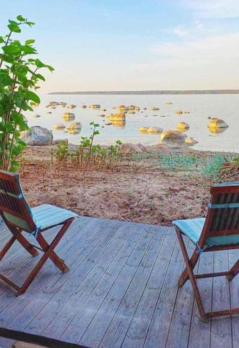 two chairs sitting on a deck near a body of water at Summerhouse only few m from the sea, with sauna! in Käsmu