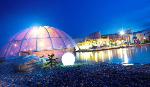 a large glass dome sitting next to a body of water at Kurhotel Pyramide Bad Windsheim in Bad Windsheim