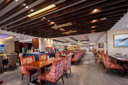 a dining room with wooden tables and chairs at New Century Hotel Qingdao in Huangdao